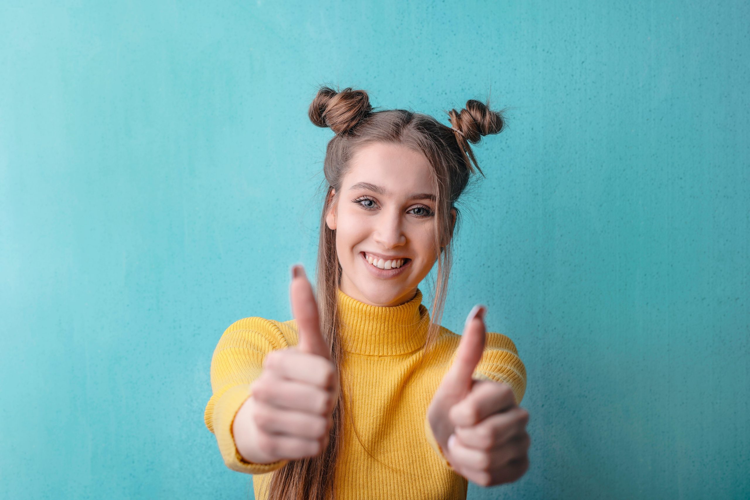 woman wearing a yellow turtleneck, giving two thumbs up